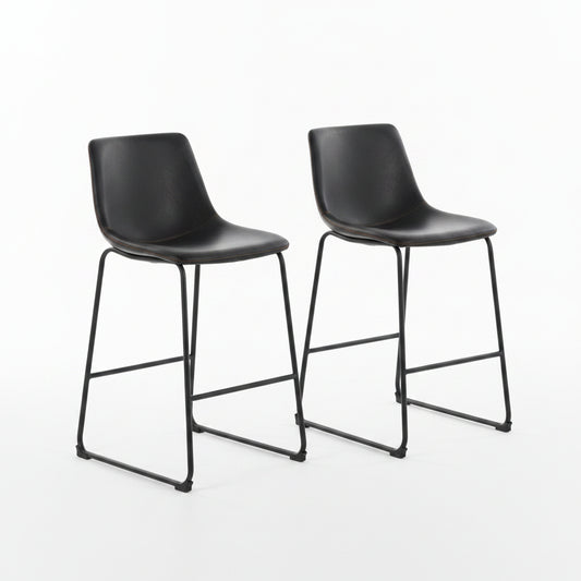 Two black bar stools in a modern kitchen setting with a wooden counter and decorative elements.